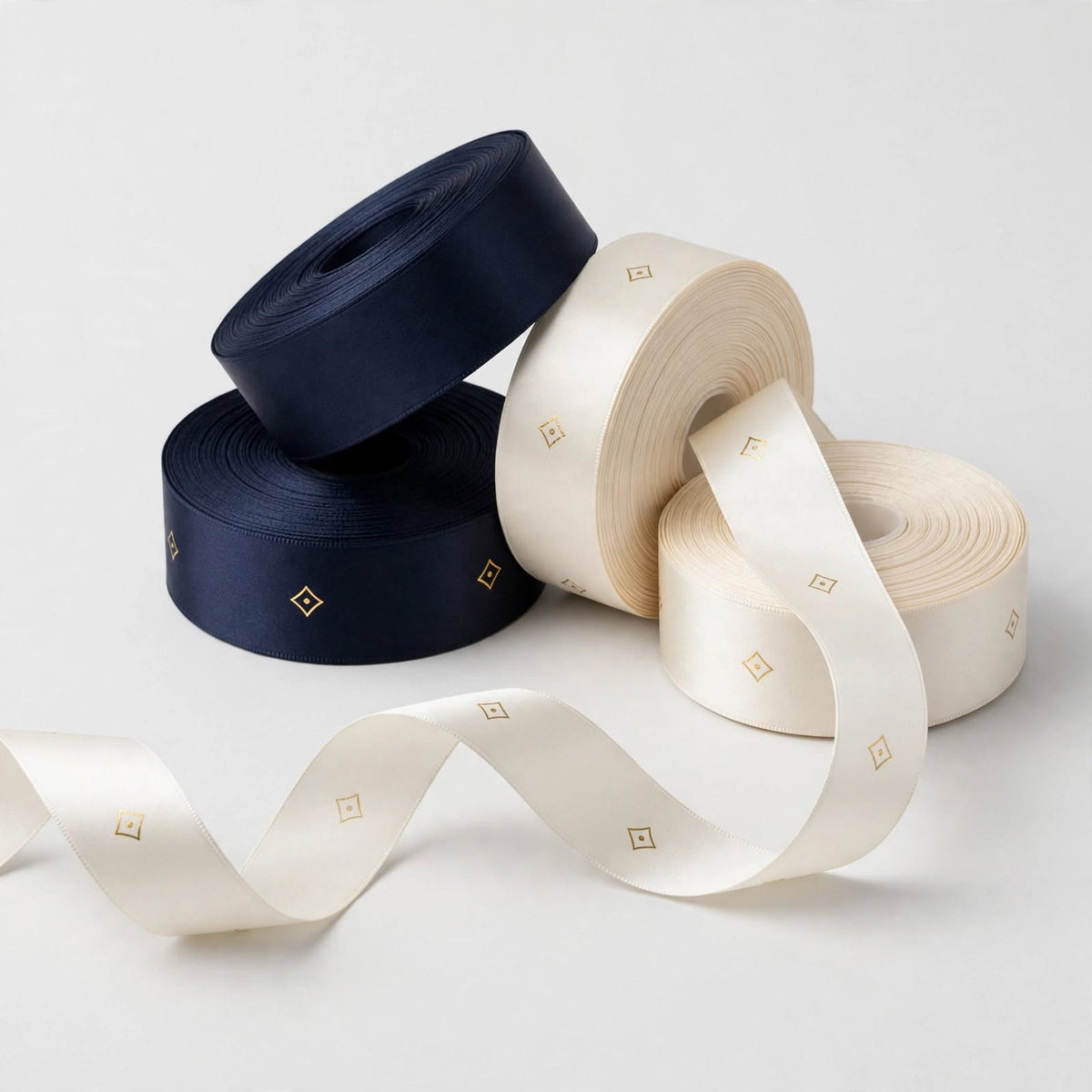Navy and ivory satin ribbon rolls printed with repeating gold logo emblem โ custom logo ribbon Dubai