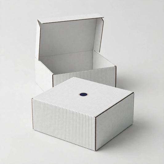 Plain white corrugated mailer box with small navy logo mark, second box open behind — custom white shipping box Dubai