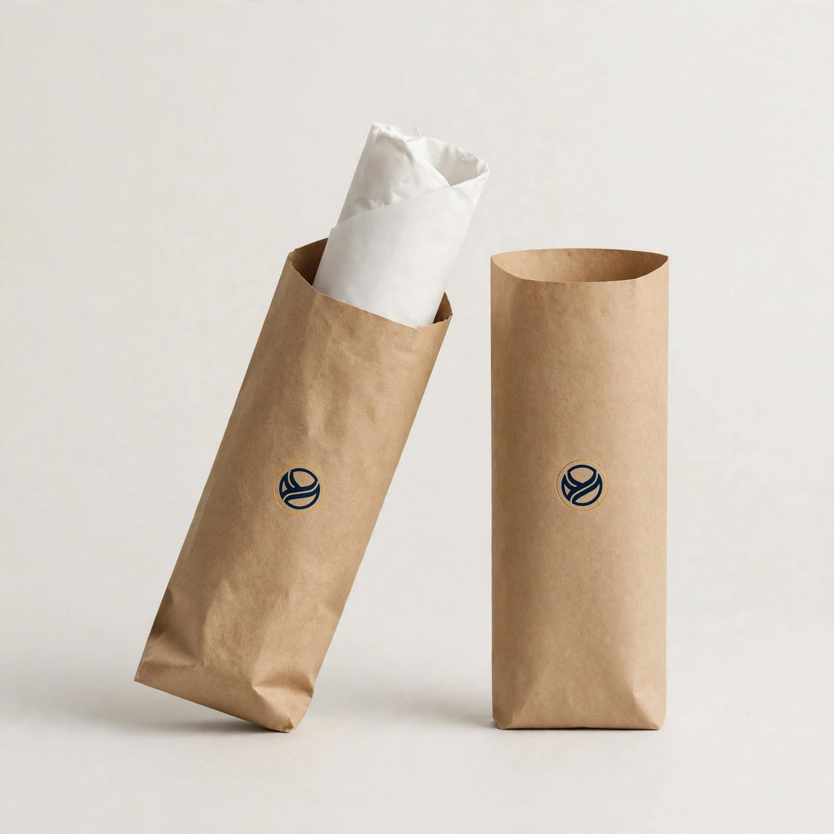 Two kraft wrap sleeves, one holding a paper-wrapped shawarma, navy logo mark — custom shawarma sleeve packaging Dubai
